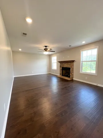 an empty room with wooden floor fireplace and windows