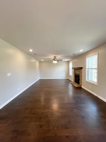 an empty room with wooden floor fireplace and windows