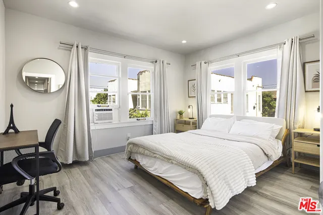 a bedroom with a bed a chair and a large window