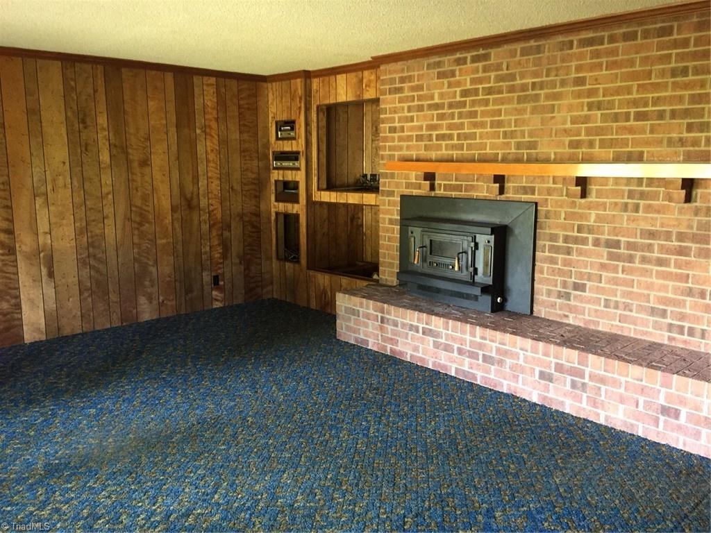 1614 Jackson Lake Road High Point, NC 27263 - Photo 2 of 15 Living room with built in shelving, wood storage and wood stove.