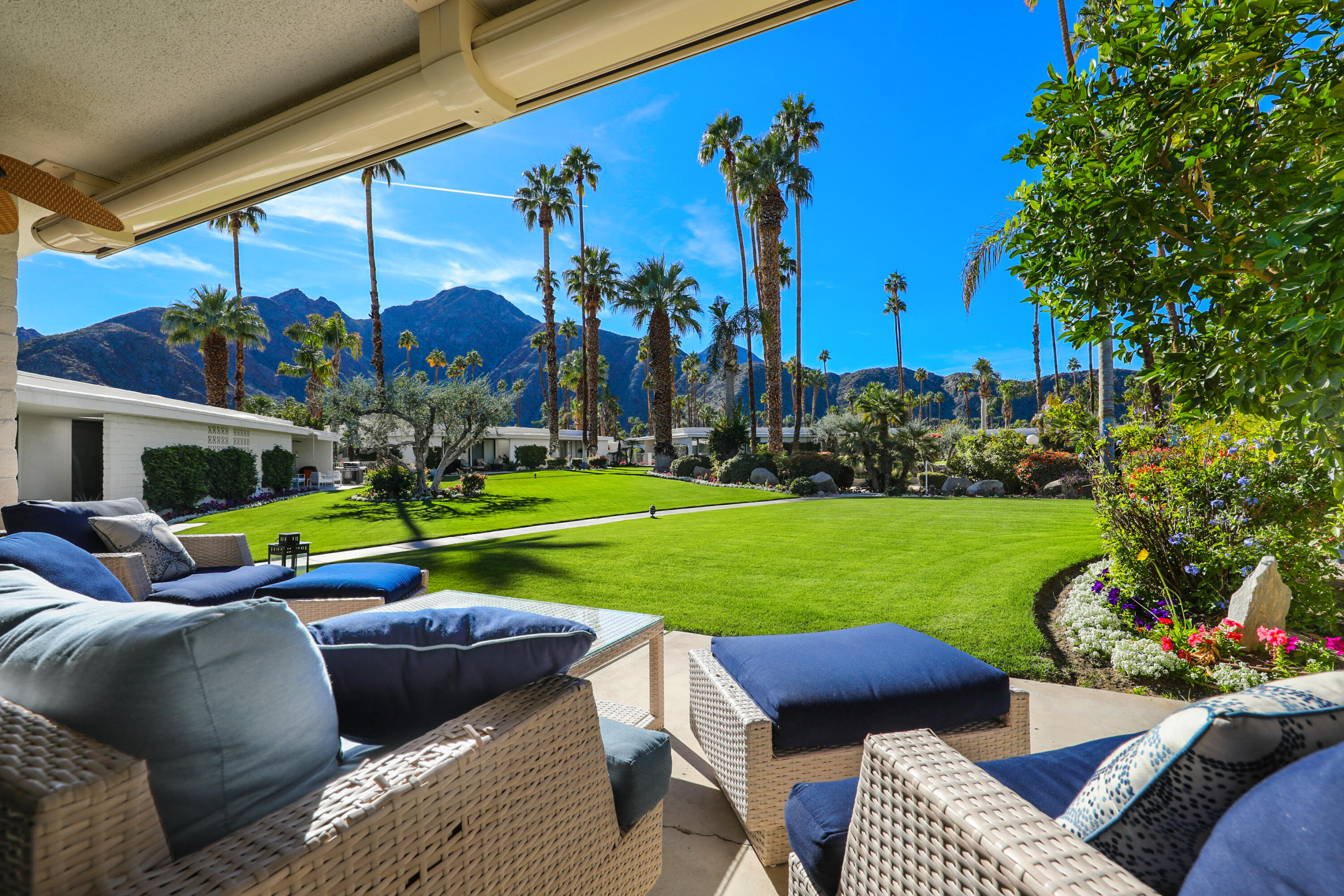 a view of a backyard with couches table and chairs and potted plants