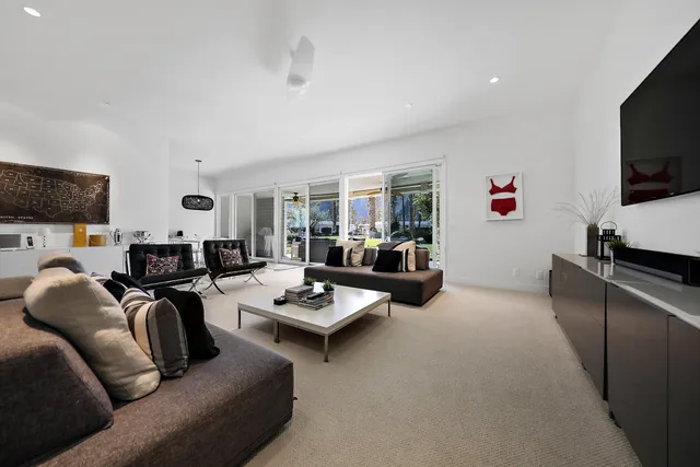 a living room with furniture kitchen view and a flat screen tv