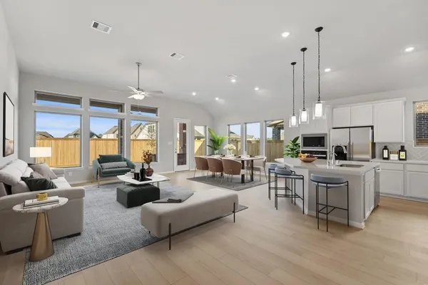 a living room with furniture kitchen area and a wooden floor