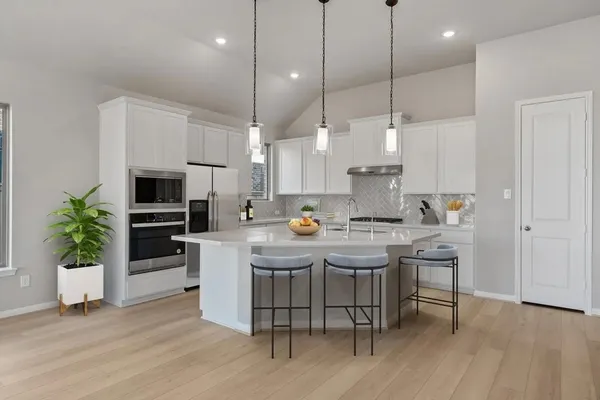 a kitchen with a sink a microwave a stove and chairs