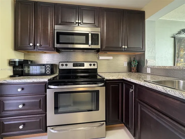 a kitchen with stainless steel appliances granite countertop wooden cabinets and a stove top oven