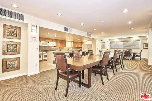 a dining room with stainless steel appliances kitchen island a table chairs and a refrigerator