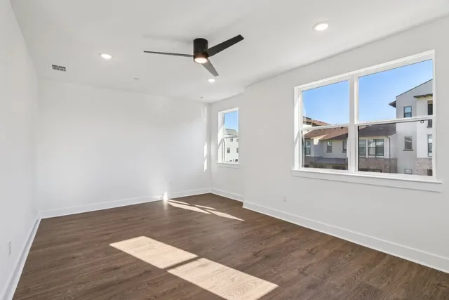 a view of an empty room with a window and wooden floor