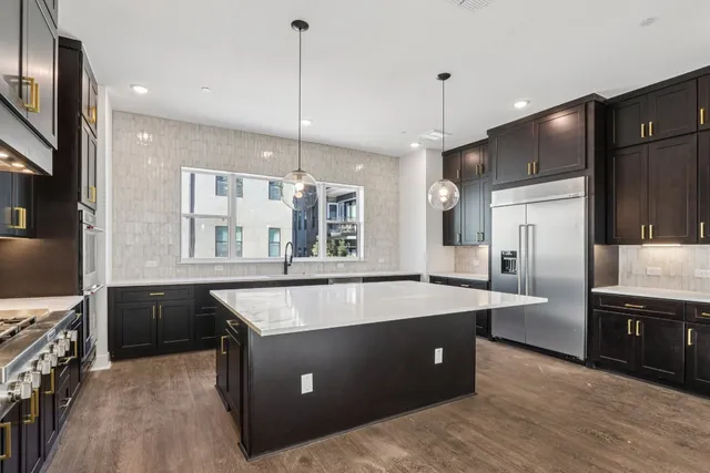 a large kitchen with stainless steel appliances a large counter top a sink refrigerator and cabinets