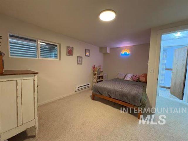 3197 Neeley Road American Falls, ID 83211 - Photo 29 of 45 Carpeted room featuring a ceiling-mounted light fixture, a window with a security grate, and a baseboard heater