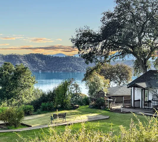 a view of a house with a big yard and large trees