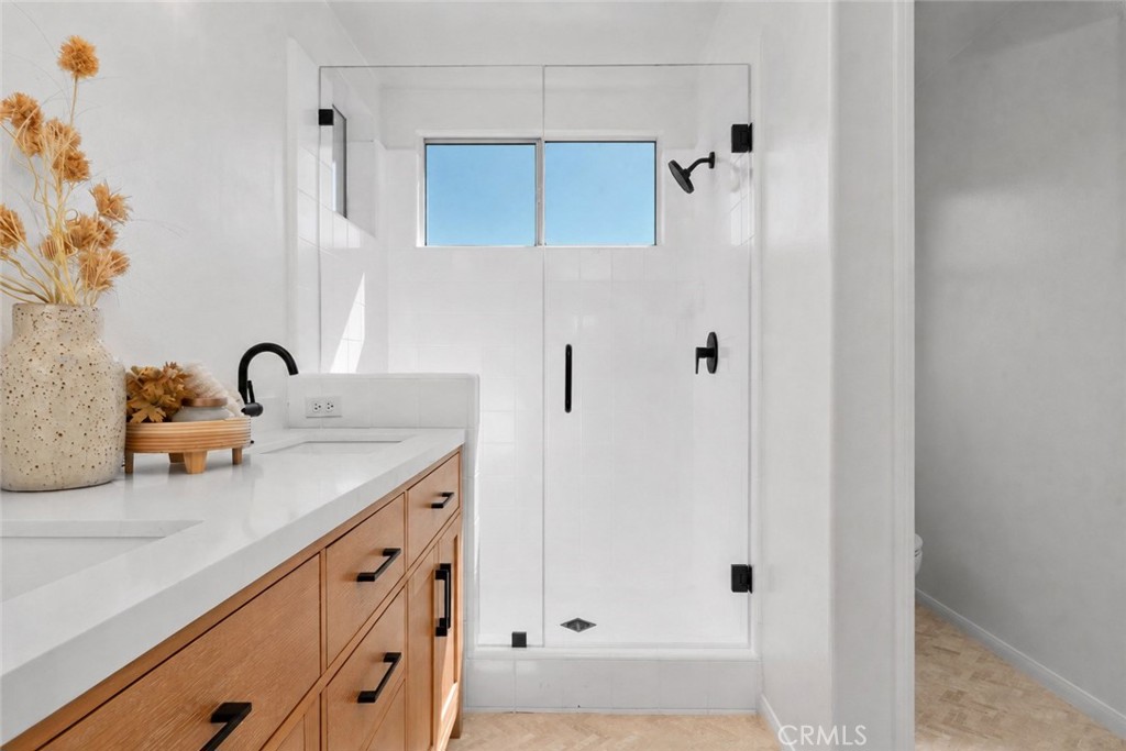 56 Acorn Ridge Rancho Santa Margarita, CA 92688 - Photo 30 of 57 Virtually Enhanced - Primary Bathroom: The walk-in shower features clean white tile, black fixtures, and an upper window that brings daylight into the space.