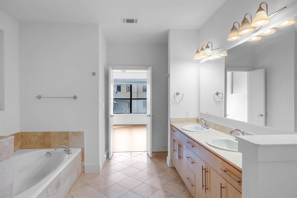 4333 Gilbert Avenue, Unit 215 Dallas, TX 75219 - Photo 11 of 19 a bathroom with a granite countertop double vanity sink a mirror and a bathtub