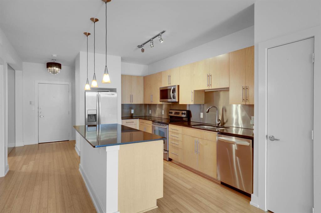 4333 Gilbert Avenue, Unit 215 Dallas, TX 75219 - Photo 4 of 19 a kitchen with stainless steel appliances granite countertop a refrigerator a sink dishwasher a stove and white countertops with wooden floor