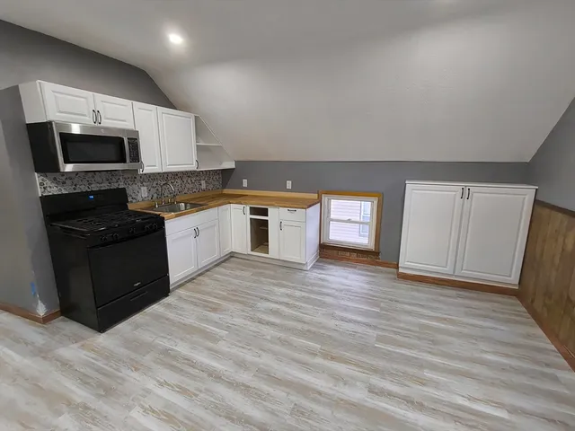 a large kitchen with stainless steel appliances granite countertop a stove a sink and a microwave