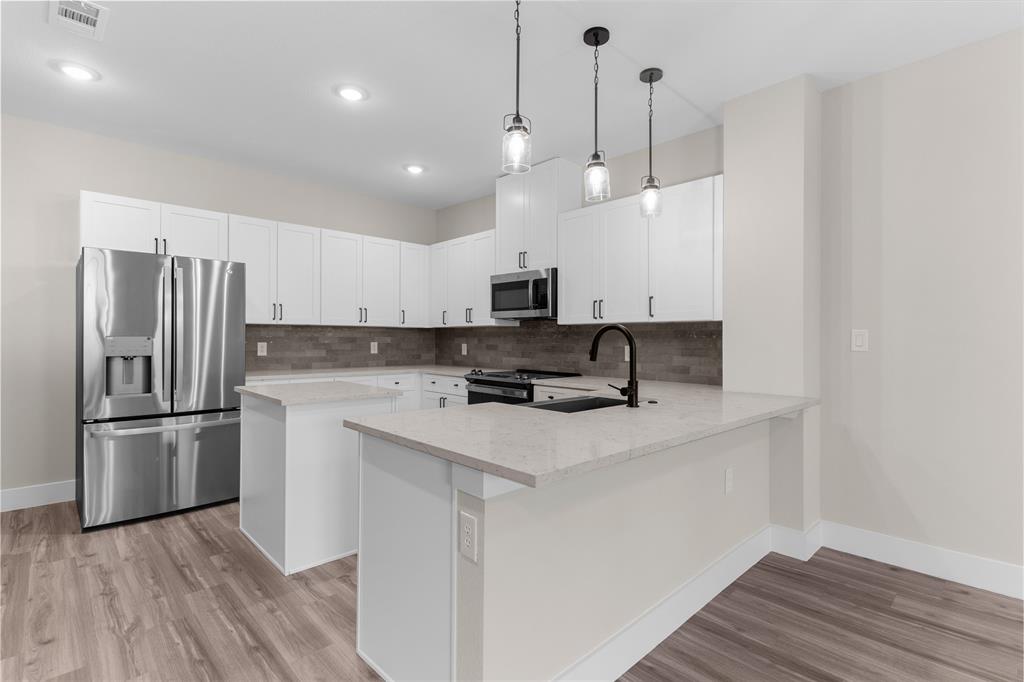 1650 Palladio Loop, Unit 2 Princeton, TX 75407 - Photo 13 of 14 Modern kitchen featuring white cabinetry, light-toned countertops, stainless steel appliances, and wood-finish flooring