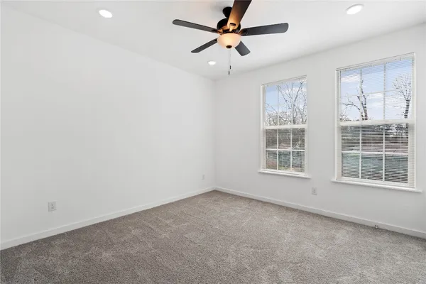 an empty room with windows and fan