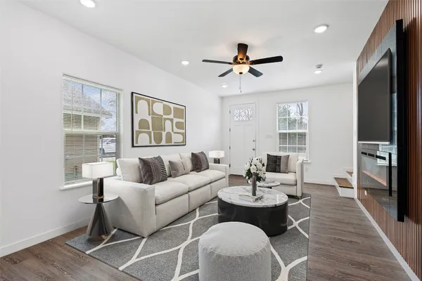 a living room with furniture a large window and wooden floor