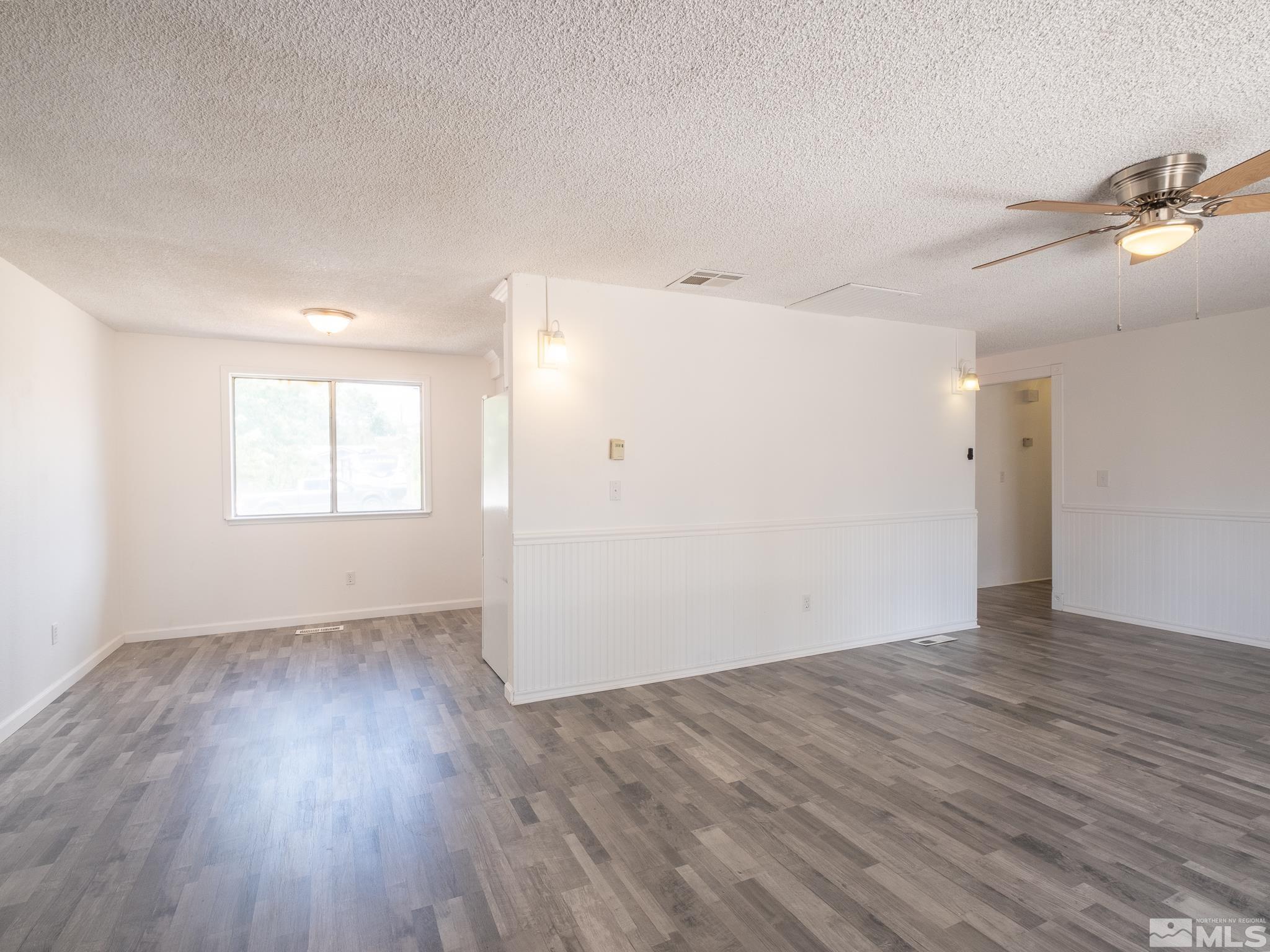 15025 Perlite Drive Reno, NV 89521 - Photo 4 of 24 an empty room with wooden floor cabinet and windows