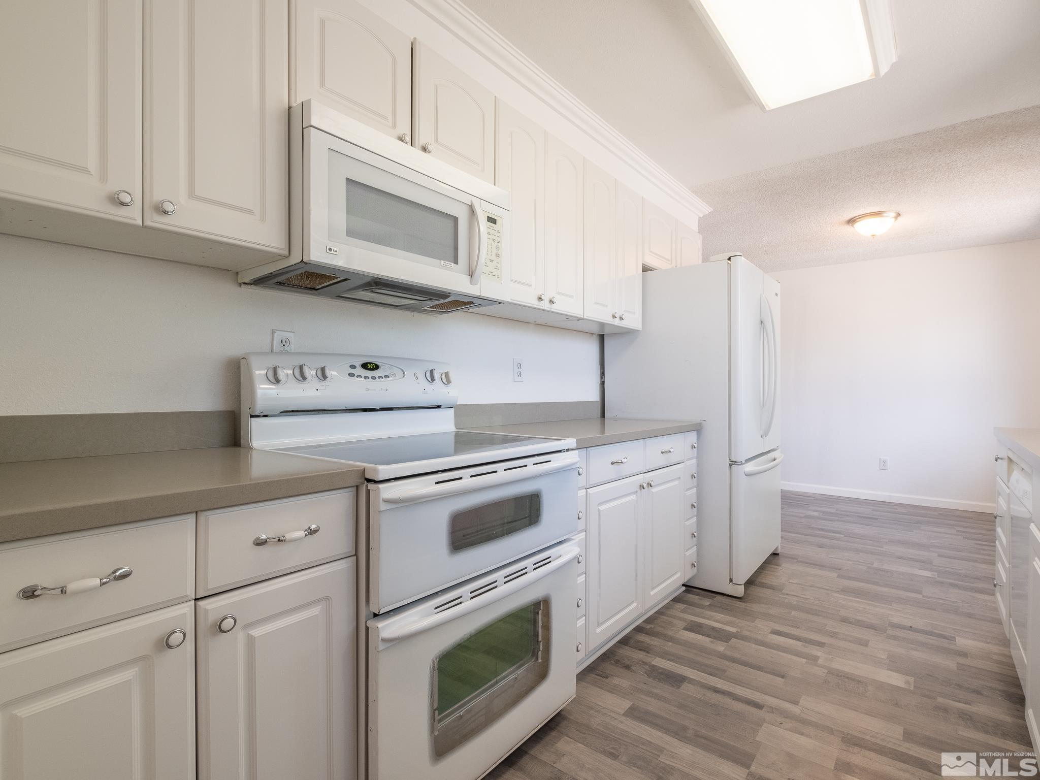 15025 Perlite Drive Reno, NV 89521 - Photo 8 of 24 a kitchen with granite countertop white cabinets and white appliances