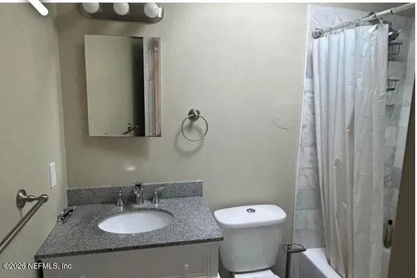 a bathroom with a granite countertop sink toilet and a mirror