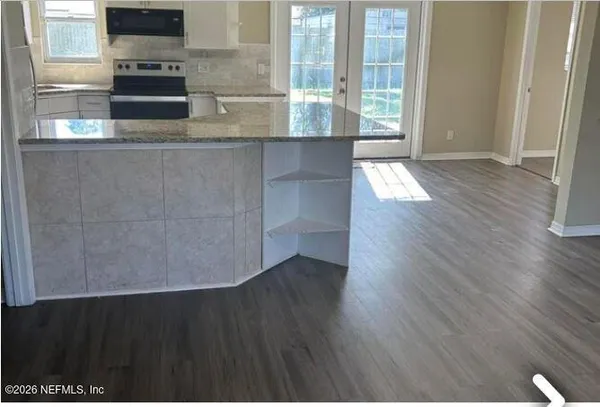 a view of a kitchen counter space with wooden floor and a fireplace
