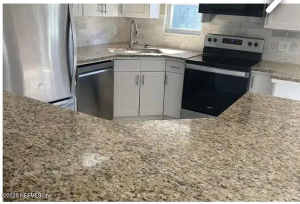 a kitchen with granite countertop a sink and a stove