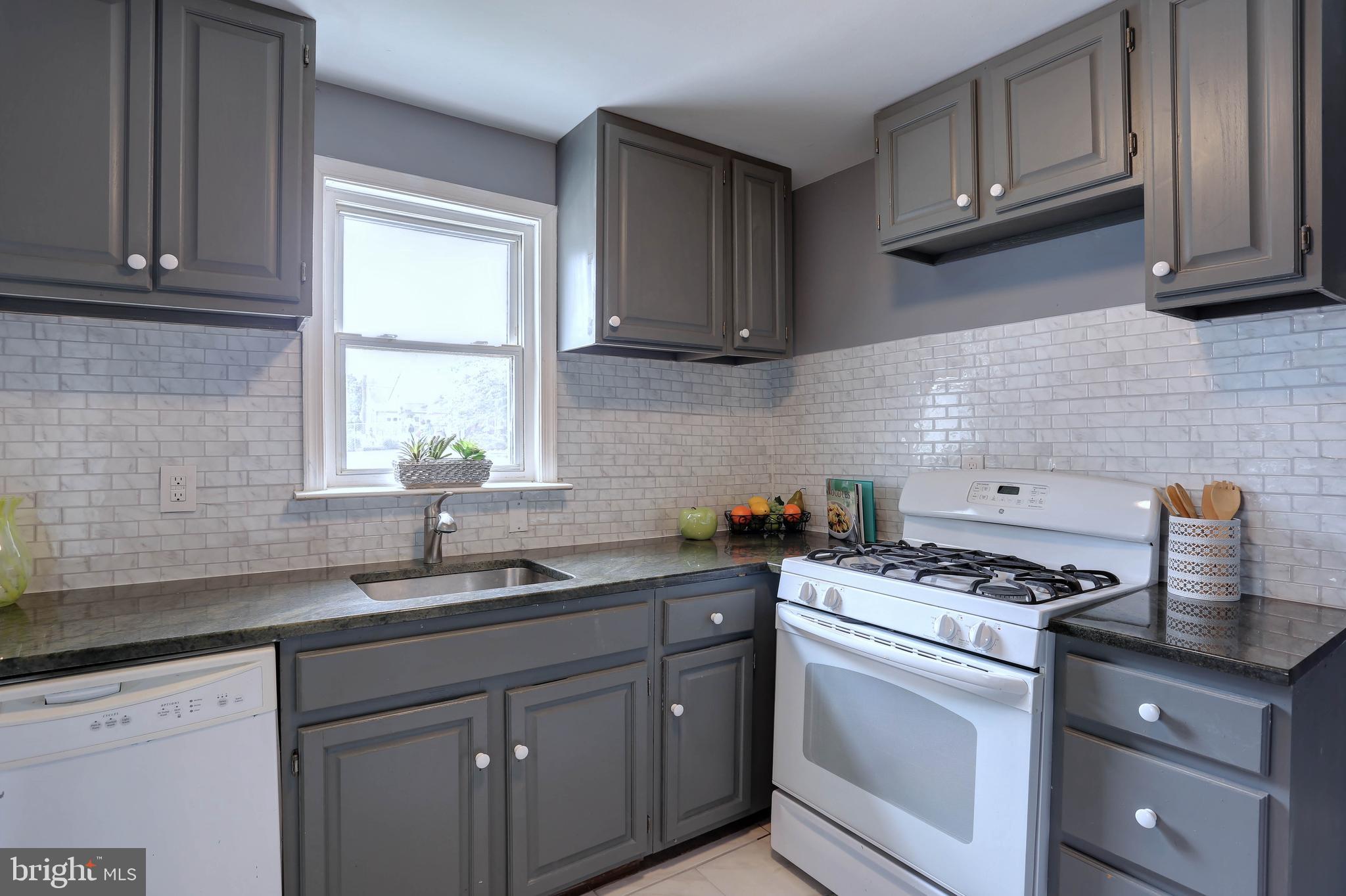 a kitchen with stainless steel appliances granite countertop a sink stove cabinets and a window