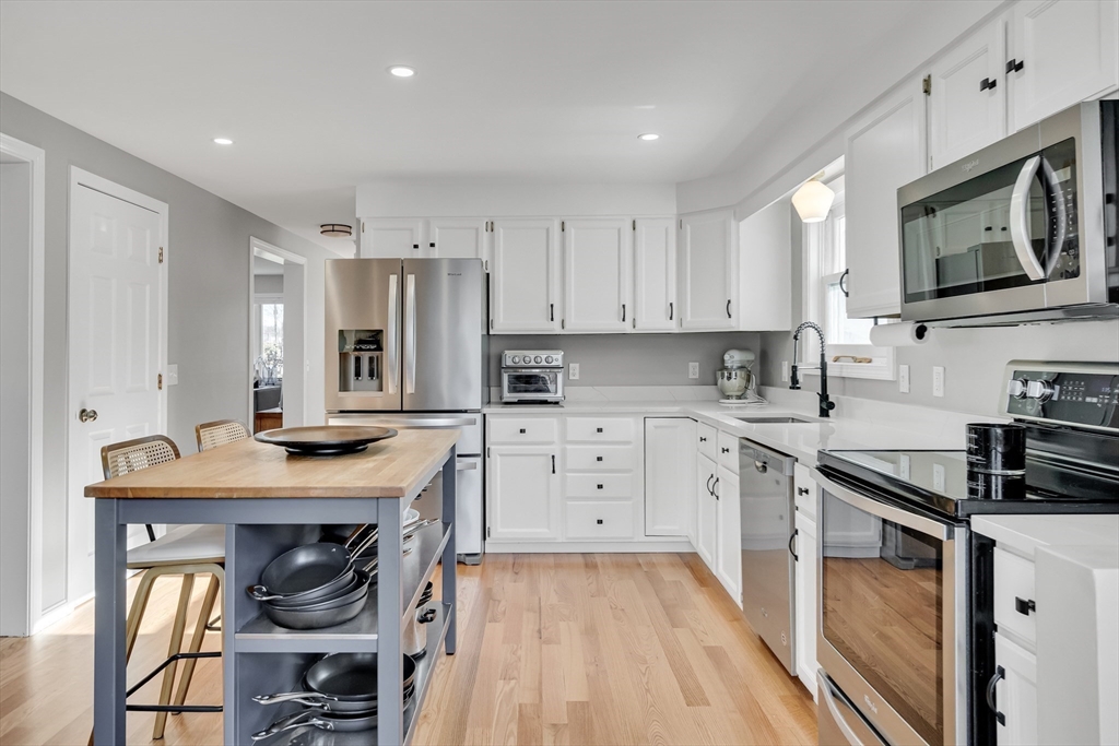 7 Long Terrace Boston, MA 02132 - Photo 14 of 42 a kitchen with stainless steel appliances granite countertop a stove top oven a sink dishwasher and a refrigerator with wooden floor