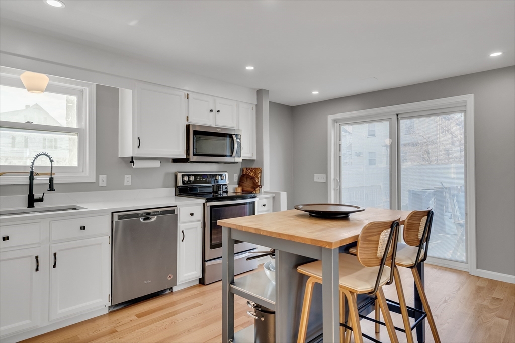 7 Long Terrace Boston, MA 02132 - Photo 16 of 42 a kitchen with stainless steel appliances granite countertop a stove a sink a microwave a dining table and chairs