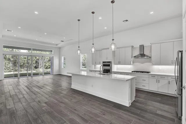 a kitchen with stainless steel appliances granite countertop a stove a sink a center island and a wooden floor