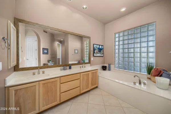 a bathroom with a tub a sink and mirror