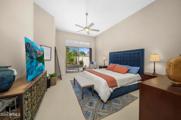 a bedroom with a bed a flat screen tv and a chandelier