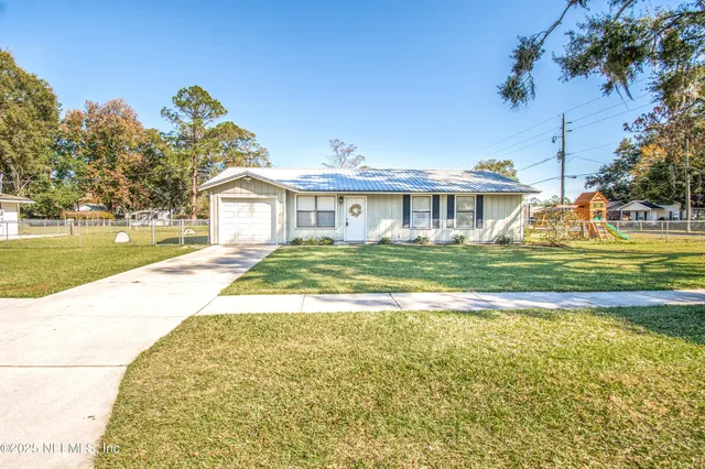 a view of a house with a big yard and palm trees