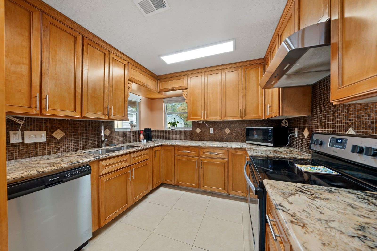 6742 Dusty Lane Conroe, TX 77306 - Photo 12 of 33 This kitchen features warm wood cabinetry, granite countertops, and stainless steel appliances. The space is well-lit with recessed lighting and a window over the sink, creating a bright and inviting atmosphere.