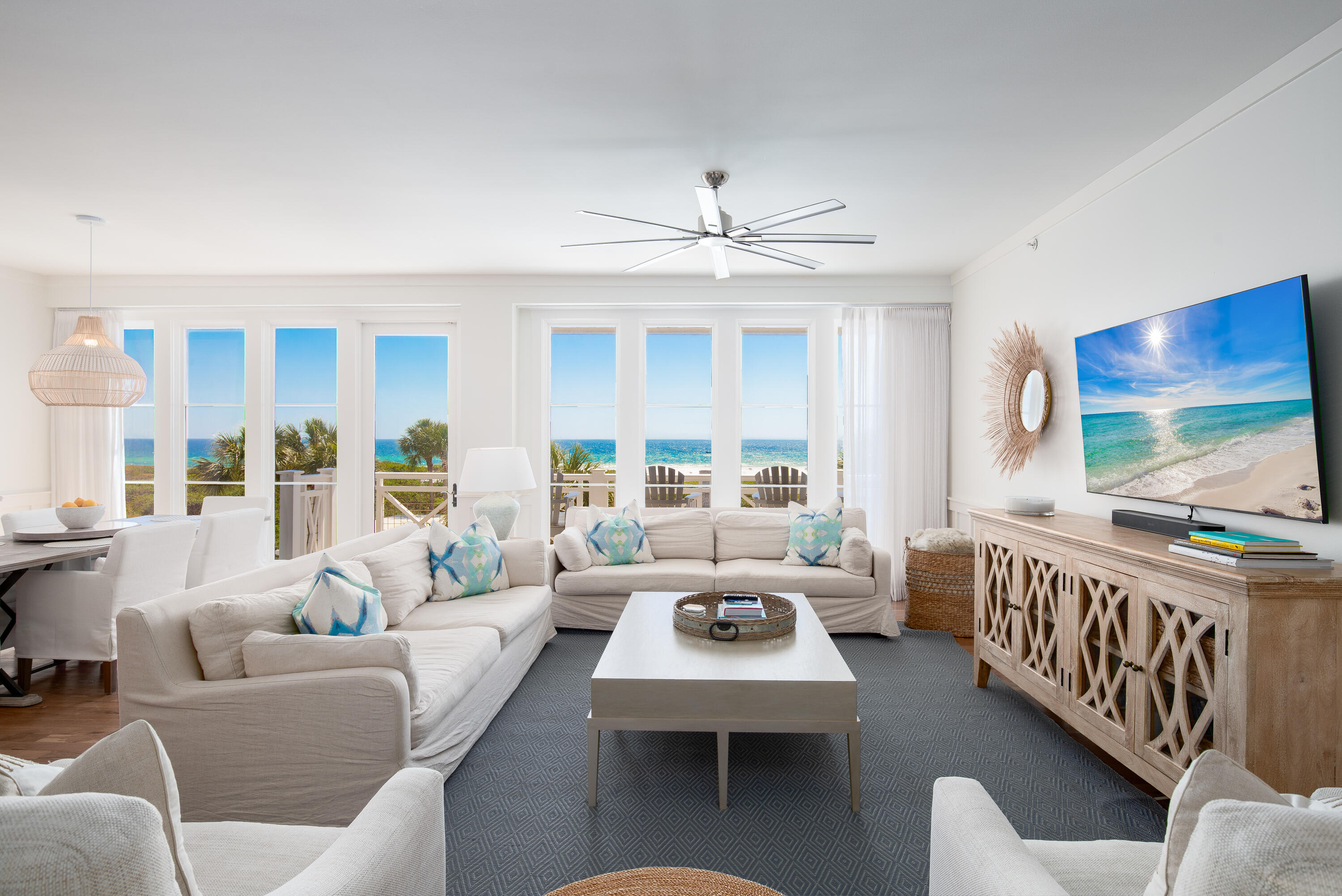 a living room with furniture two large window and a flat screen tv
