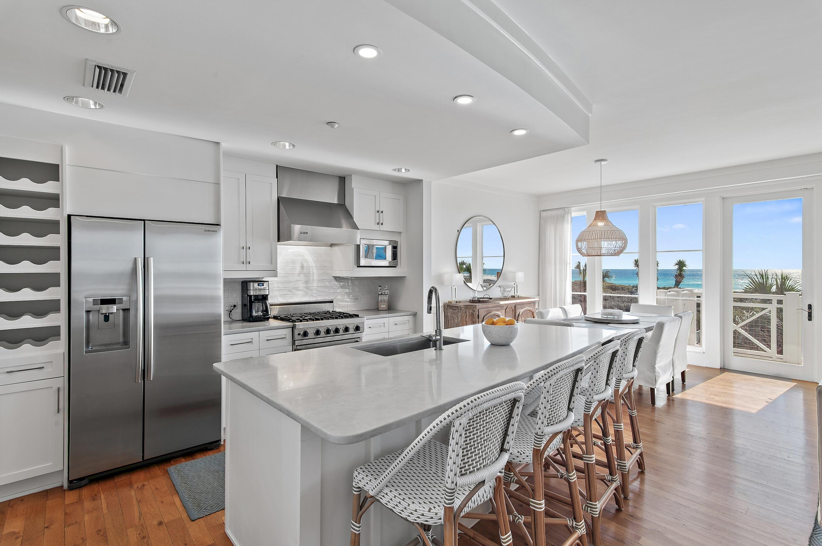 337 Bridge Lane, Unit 312B Watersound, FL 32461 - Photo 6 of 37 a kitchen with stainless steel appliances granite countertop a stove a refrigerator a sink a dining table and chairs with wooden floor