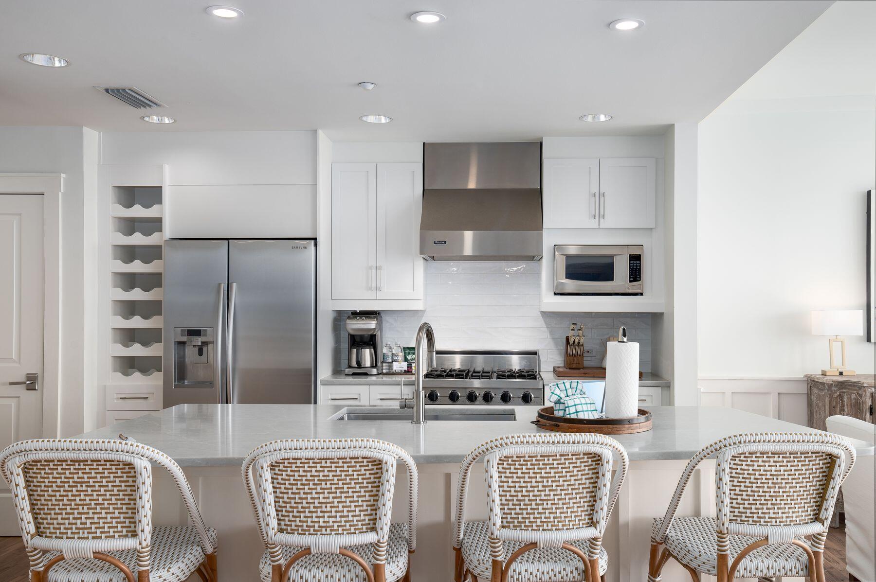 337 Bridge Lane, Unit 312B Watersound, FL 32461 - Photo 7 of 37 a kitchen with stainless steel appliances granite countertop a sink a stove a refrigerator cabinets and a dining table with wooden floor