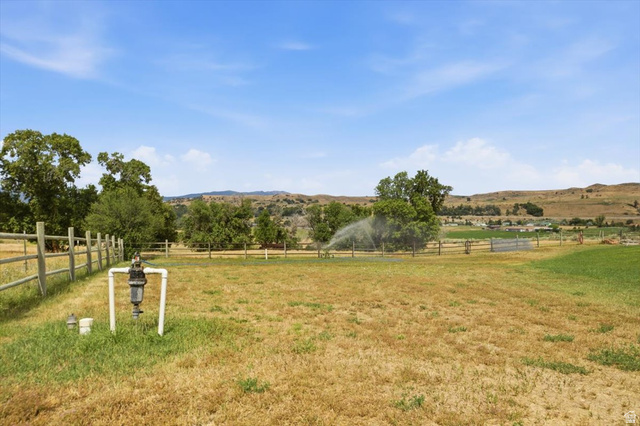 3123 East Riverdale Road Preston, ID 83263 - Photo 33 of 52 Expansive open land featuring a wood-rail fence, scattered mature trees, and an irrigation system