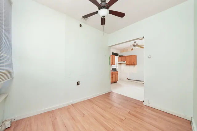 an empty room with wooden floor and ceiling fan