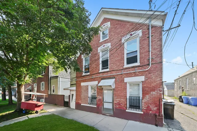 a view of a brick house with a yard and large tree