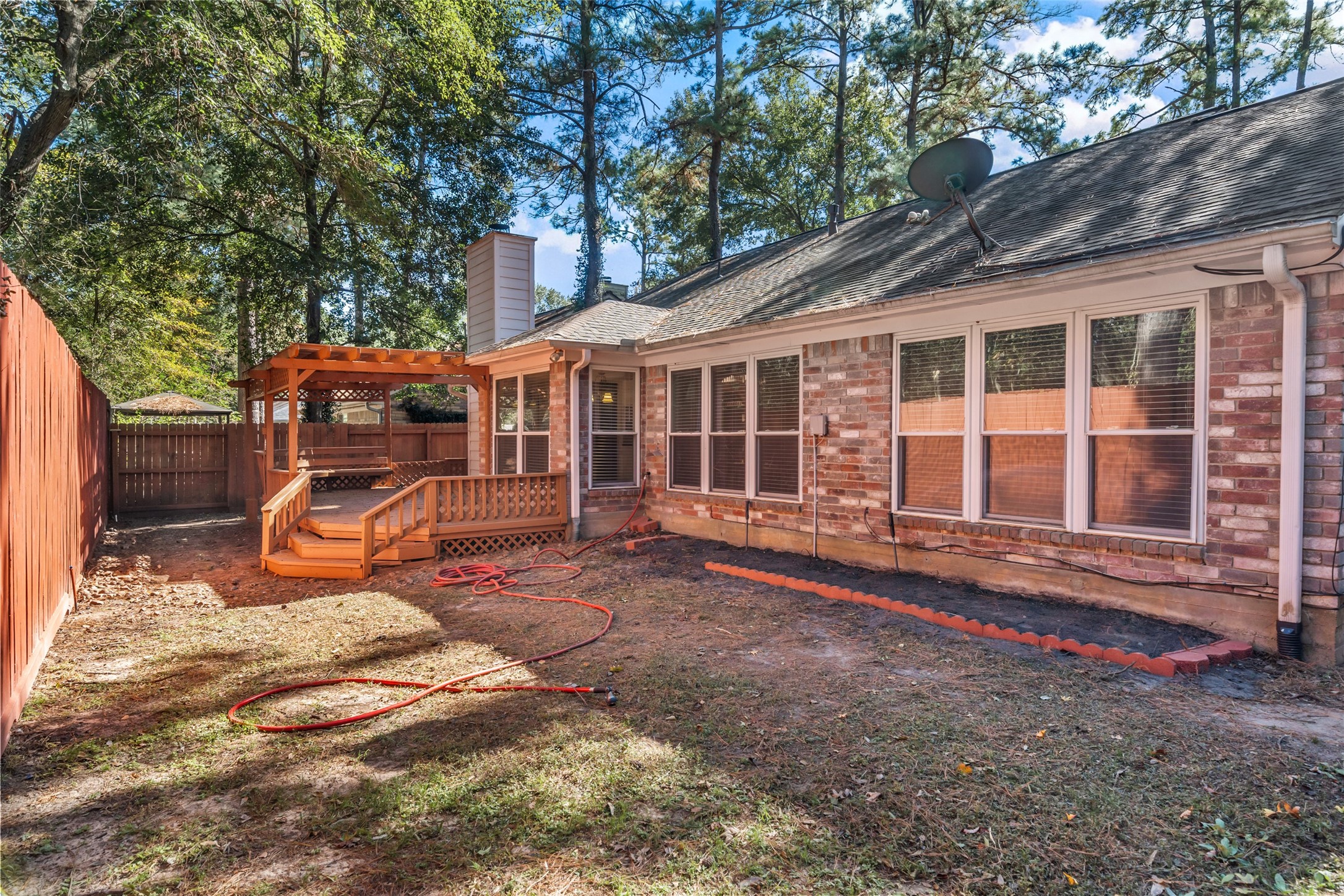 107 Sandpebble Drive The Woodlands, TX 77381 - Photo 30 of 30 a view of a house with backyard wooden fence and a large tree
