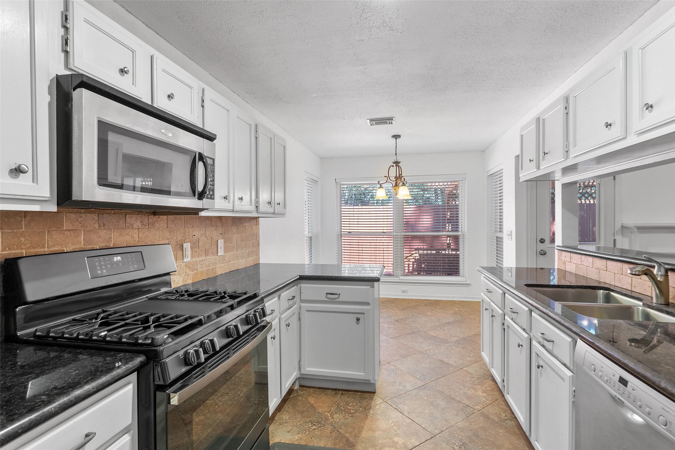 107 Sandpebble Drive The Woodlands, TX 77381 - Photo 8 of 30 a kitchen with stainless steel appliances granite countertop a stove and a microwave