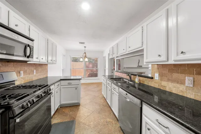 a large kitchen with stainless steel appliances granite countertop a lot of cabinets a stove and a sink