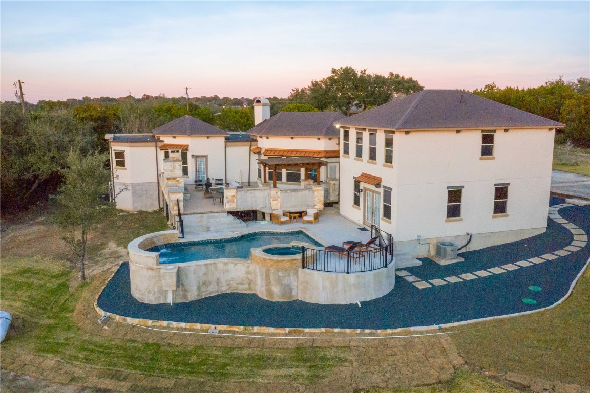 Back of property featuring a patio area and a pool with connected hot tub