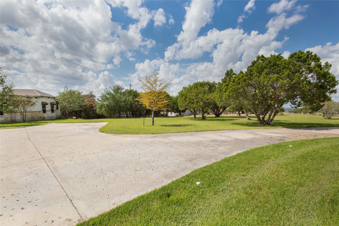 11209 Southwest Oaks Austin, TX 78737 - Photo 3 of 34 View of property's community with a lawn and curved driveway