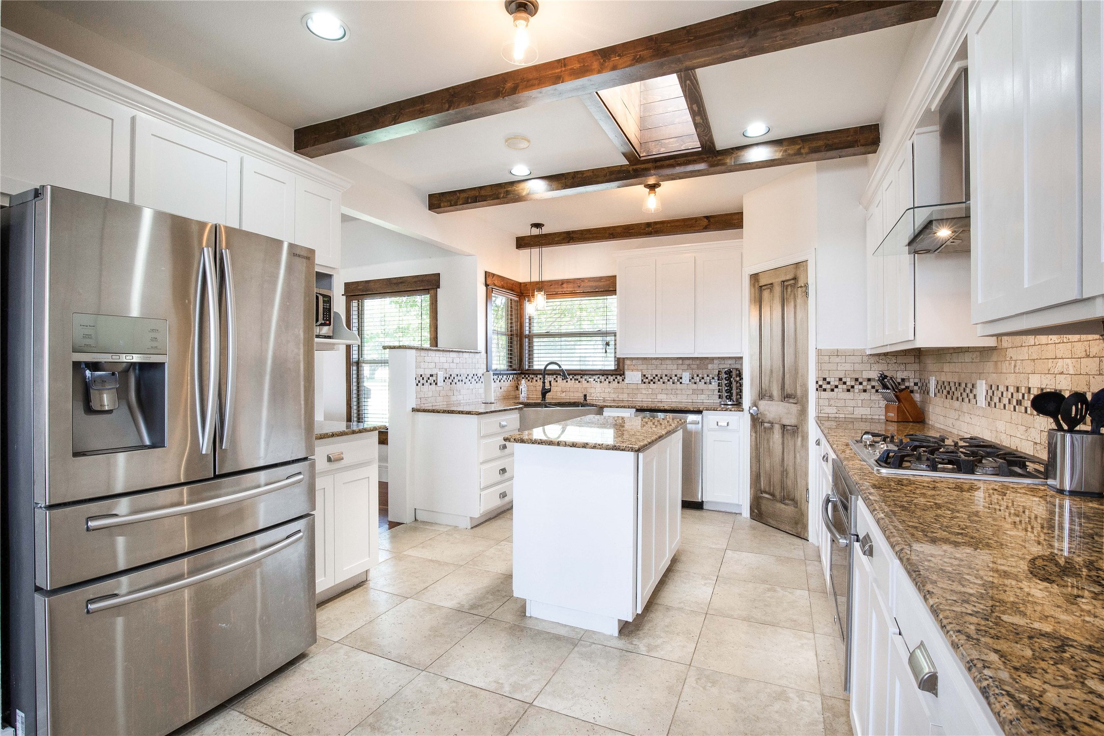 11209 Southwest Oaks Austin, TX 78737 - Photo 10 of 34 Kitchen with appliances with stainless steel finishes, white cabinets, dark stone countertops, a center island, and decorative backsplash