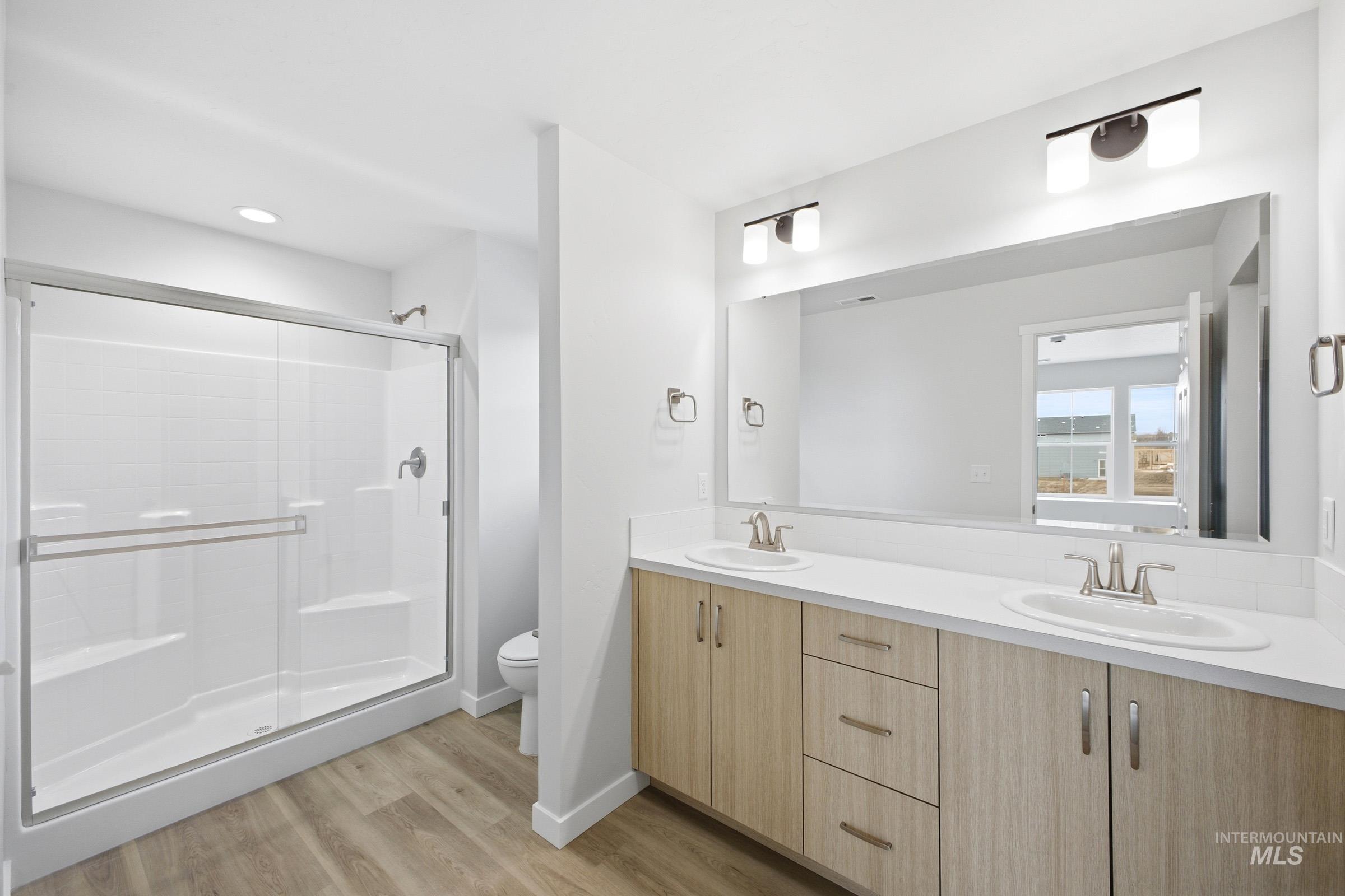 13718 Inman Court Caldwell, ID 83607 - Photo 19 of 20 Full bathroom featuring double vanity, a shower stall, and light wood-type flooring