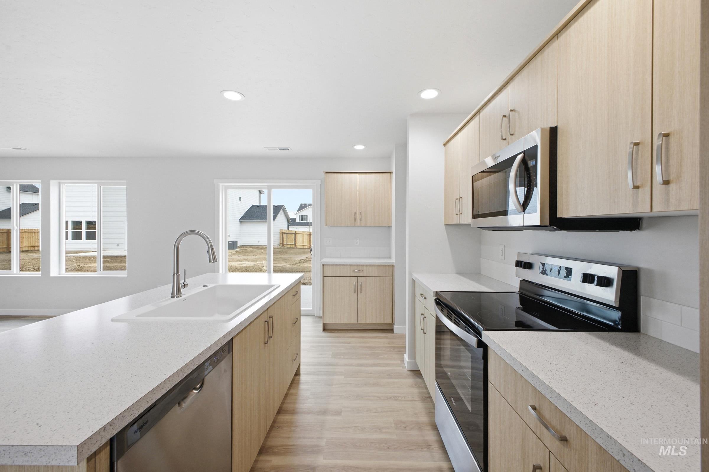 13718 Inman Court Caldwell, ID 83607 - Photo 5 of 20 Kitchen featuring stainless steel appliances, light wood finish cabinets, light wood finished floors, recessed lighting, and a center island with sink