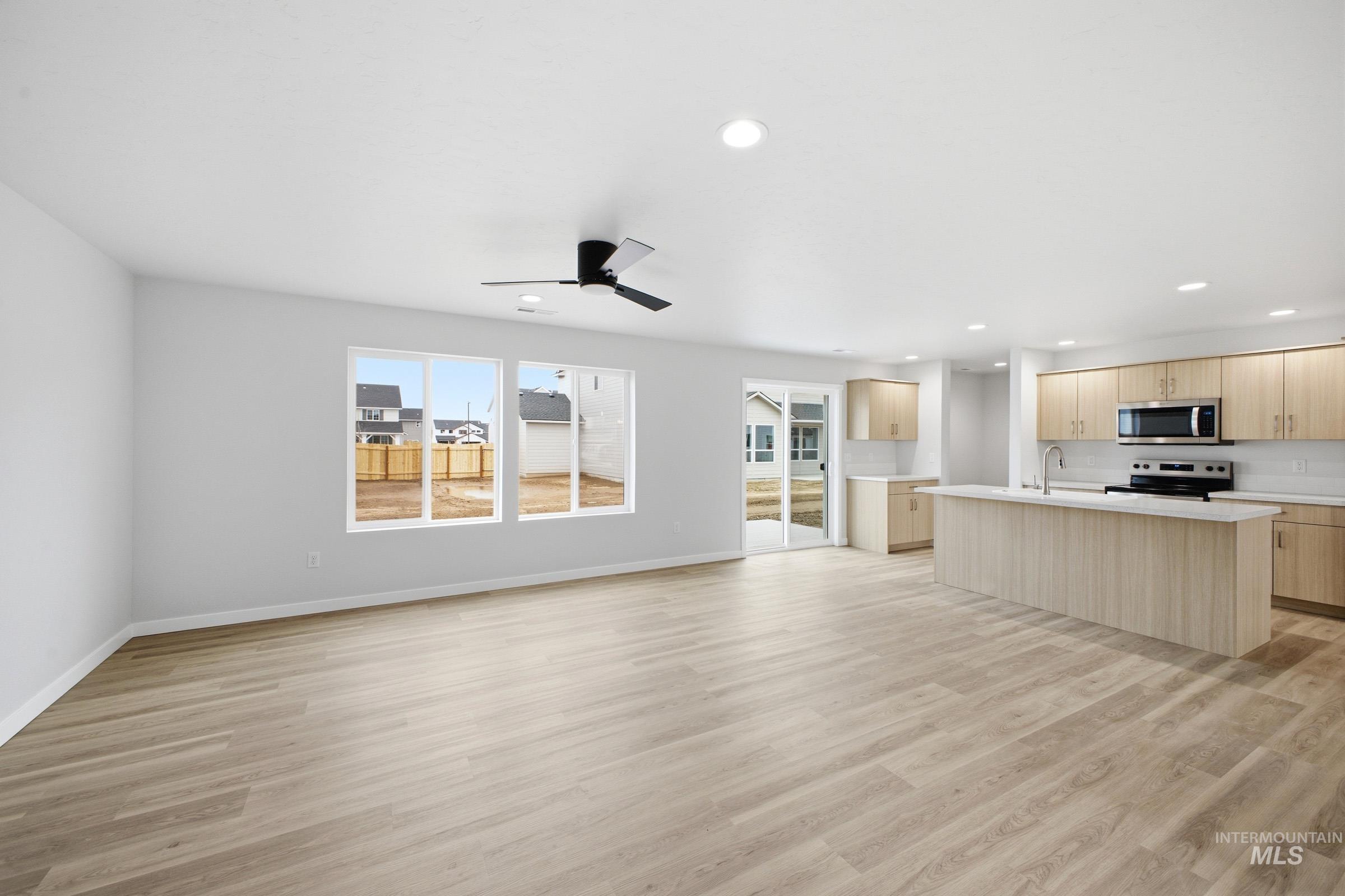 13718 Inman Court Caldwell, ID 83607 - Photo 7 of 20 Kitchen featuring a center island with sink, light countertops, light wood finish cabinetry, stainless steel appliances, and a ceiling fan