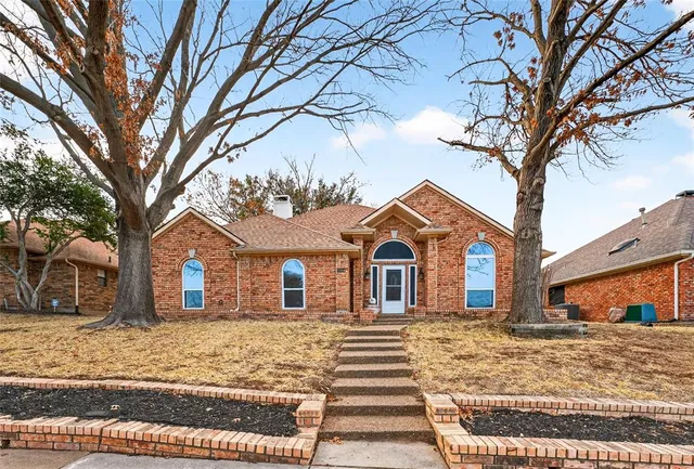 a front view of a house with a yard and large trees